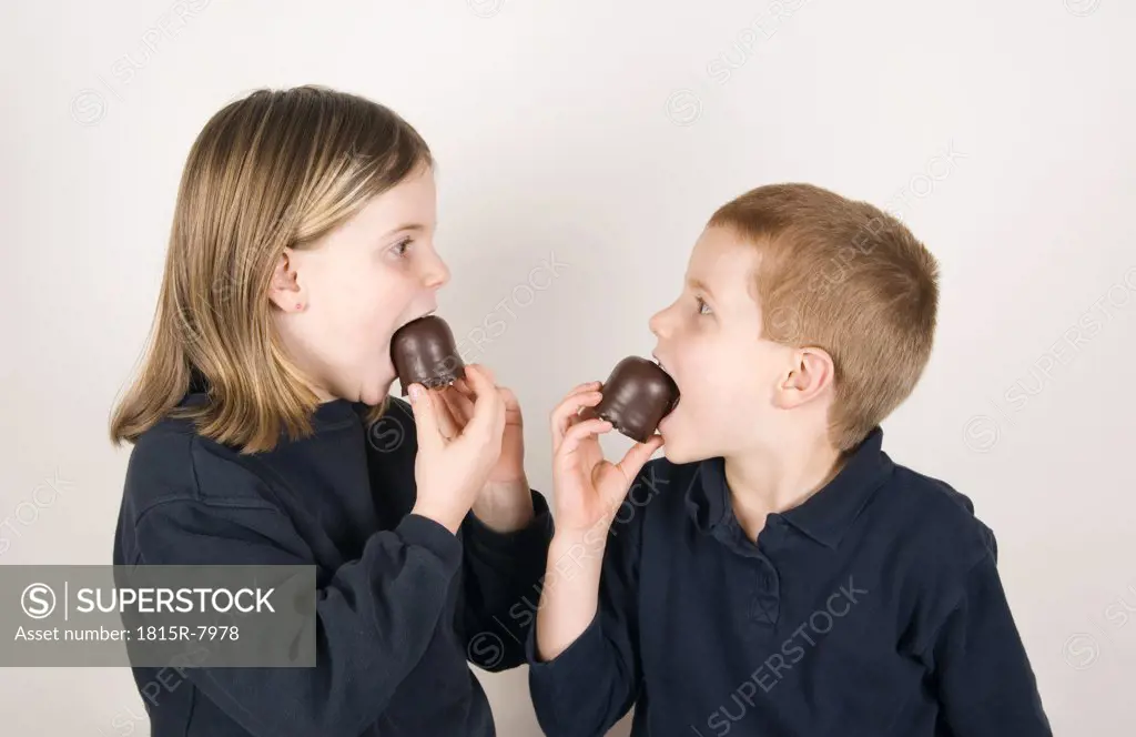 Boy and girl (8-9) eating chocolate marshmallows