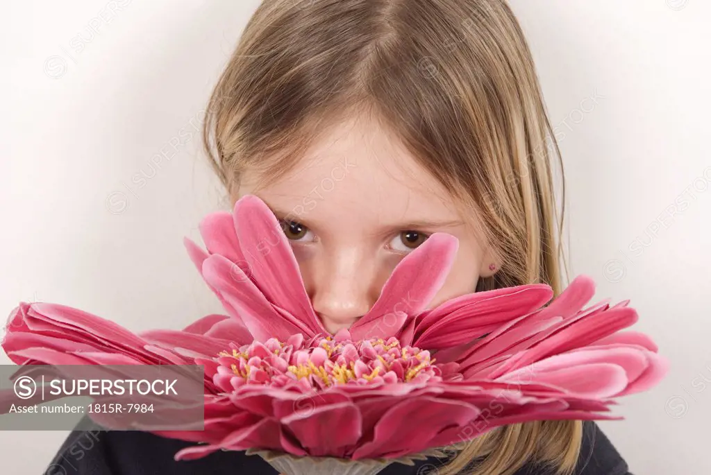 Blonde girl (8-9) nosing a flower, portrait