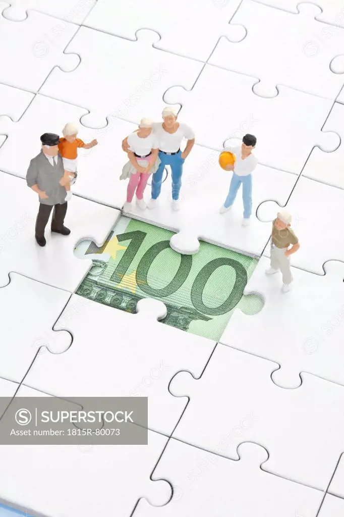 Figurine standing on jigsaw piece and watching 100 euro note