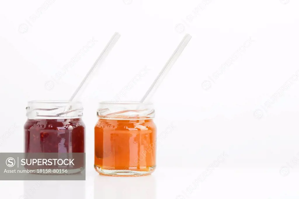 Spoon in jam jar on white background