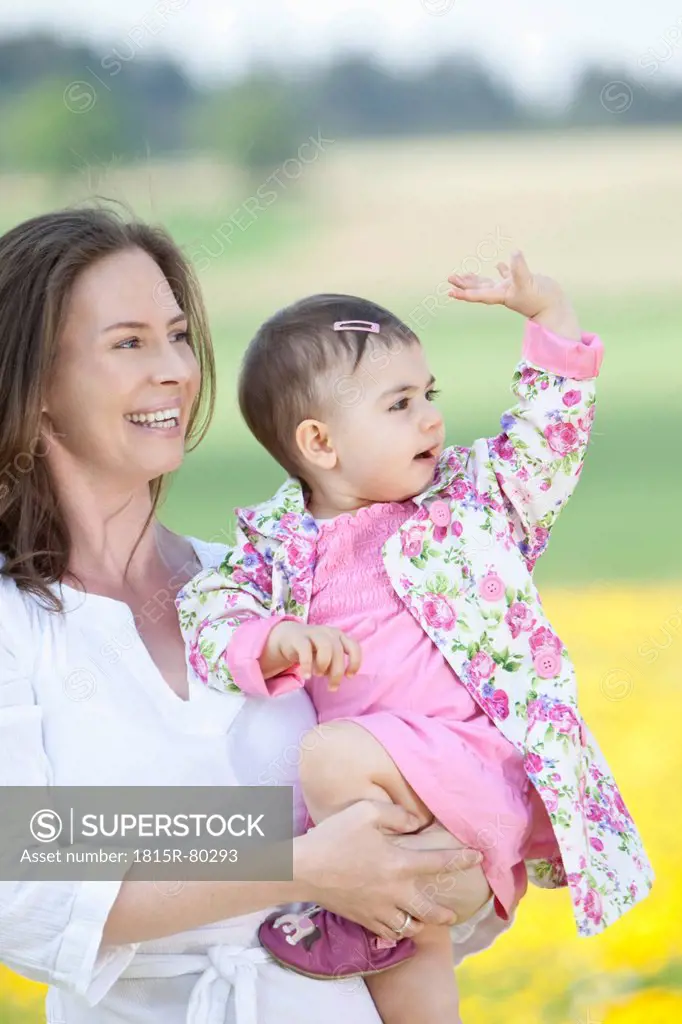 Germany, Bavaria, Mother holding her baby girl, smiling, waving