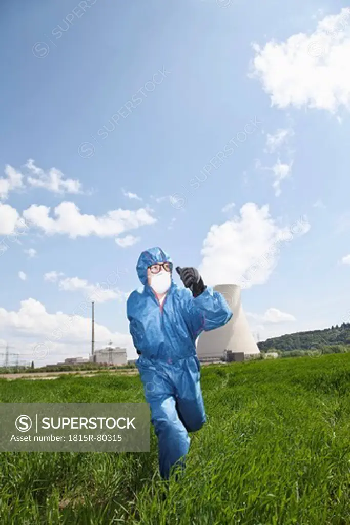 Germany, Bavaria, Unterahrain, Man with protective workwear running in field at AKW Isar