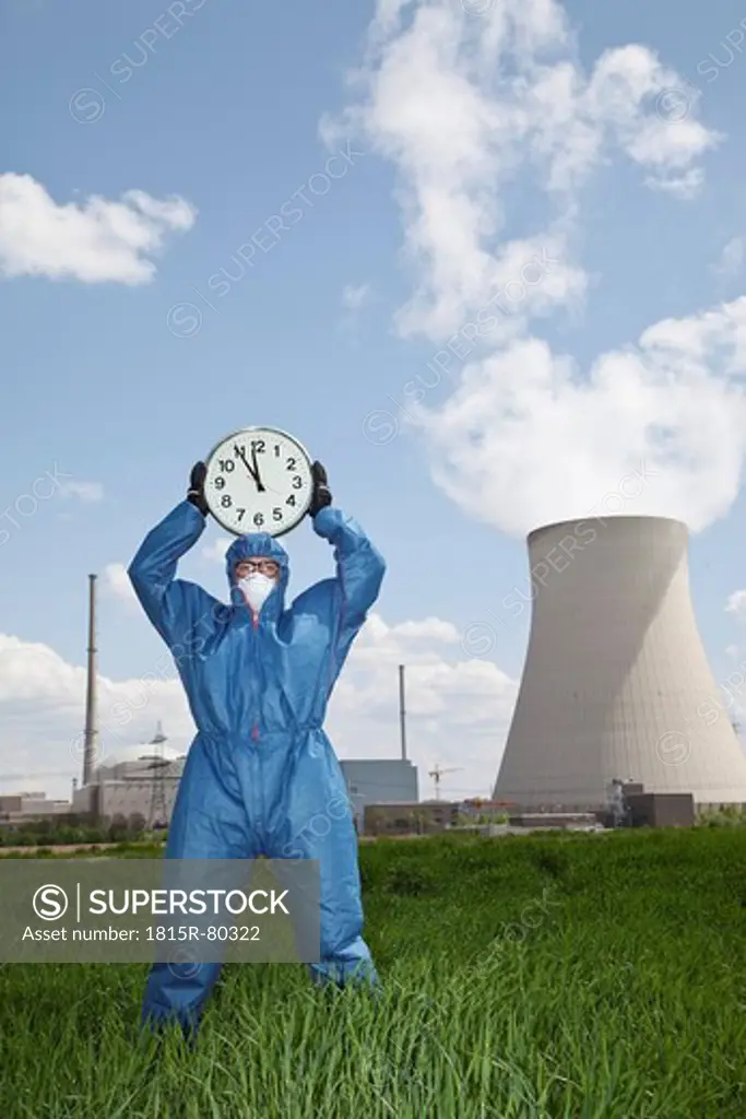 Germany, Bavaria, Unterahrain, Man in protective workwear holding clock at AKW Isar