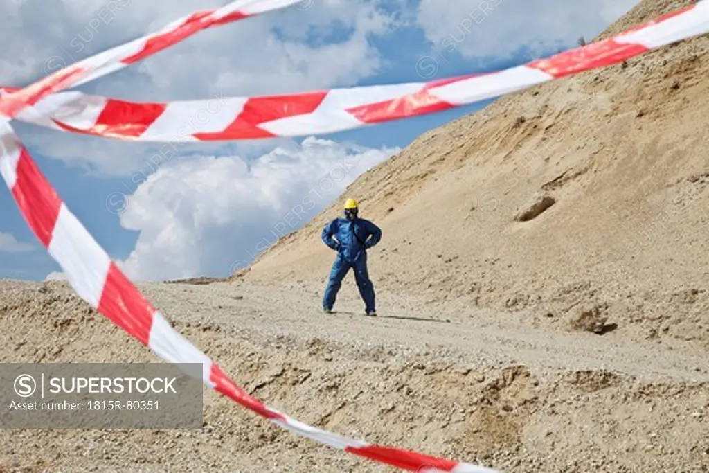Germany, Bavaria, Man in protective wear on sand dune and cordon tape in foreground
