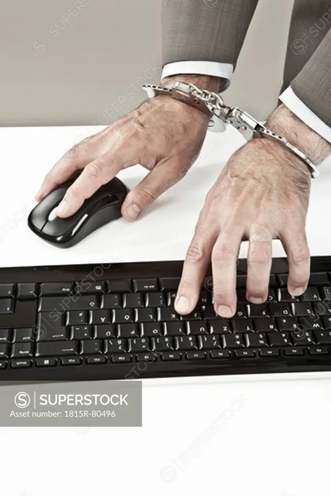 Close up of businessman´s hand cuffed while cyber crime