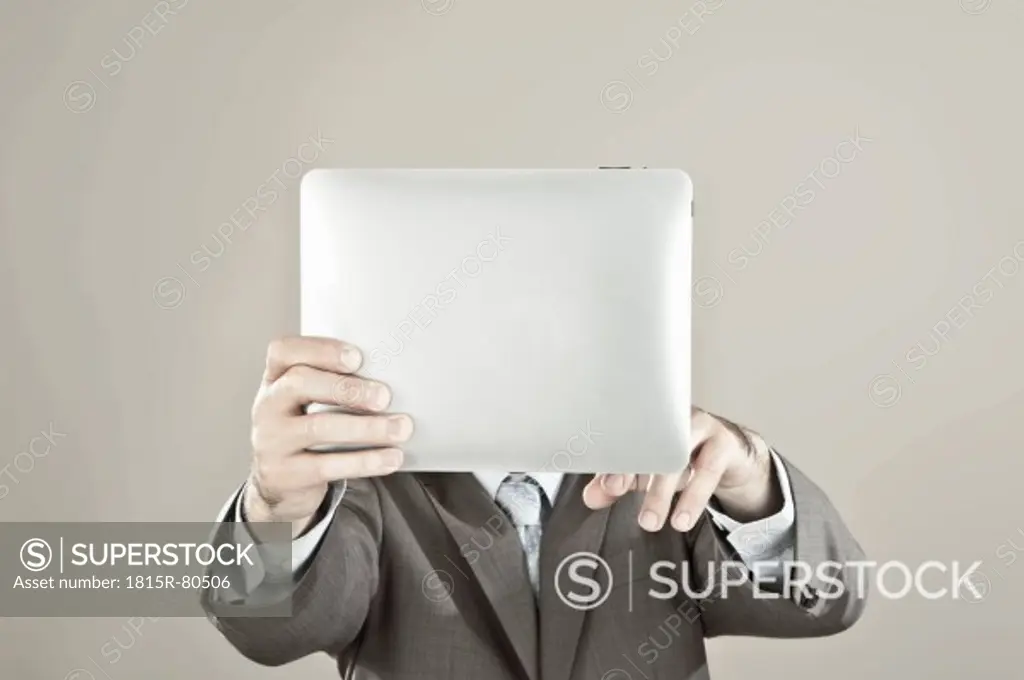 Close up of businessman holding ipad in front of his face against grey background