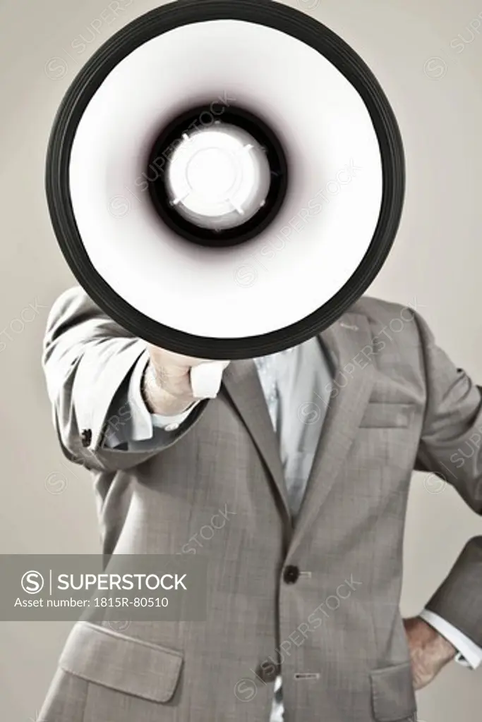 Close up of businessman with face covered with megaphone against grey background
