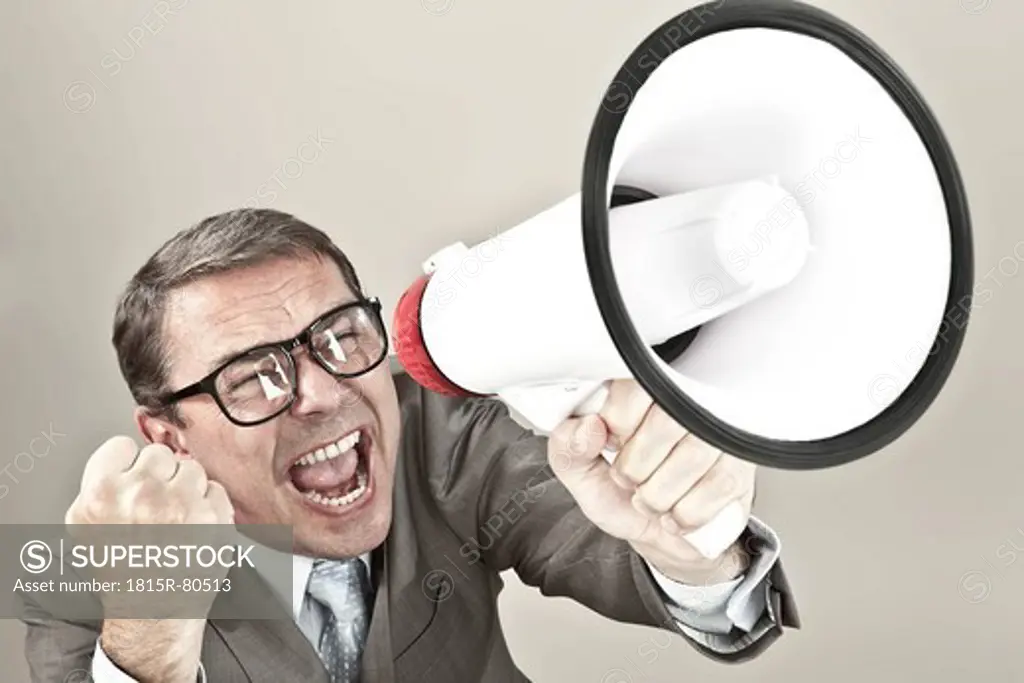 Close up of businessman screaming through megaphone against grey background