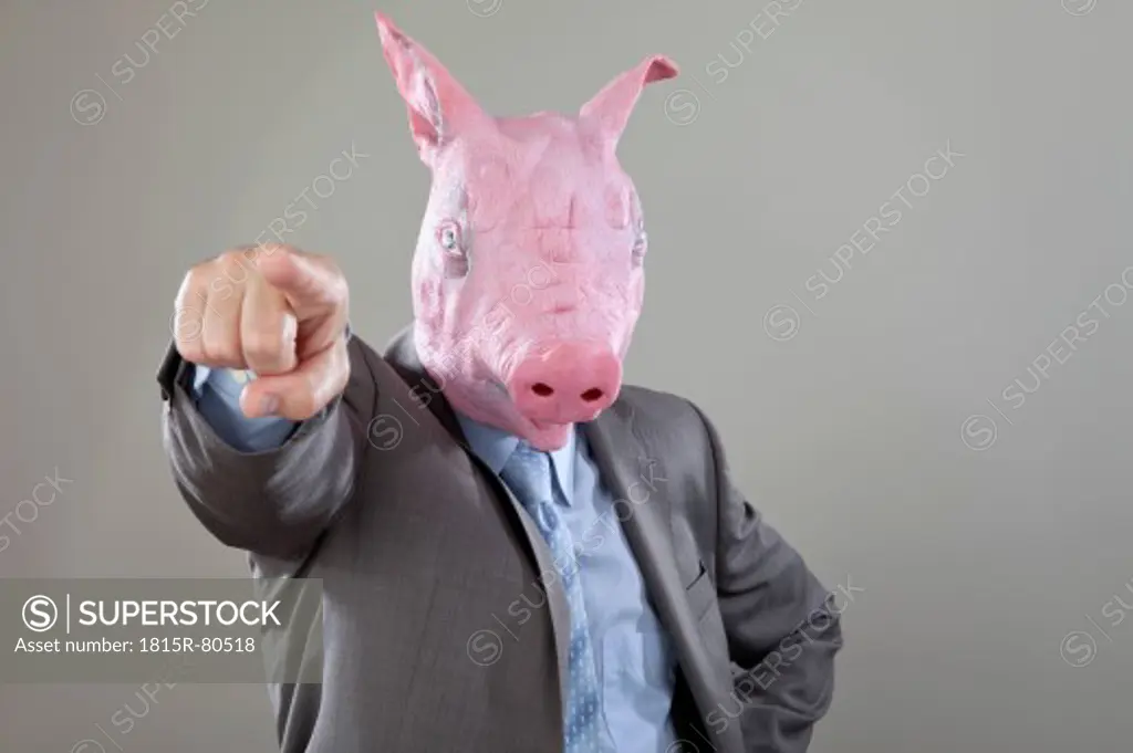 Close up of businessman with pigs head pointing in office against grey background