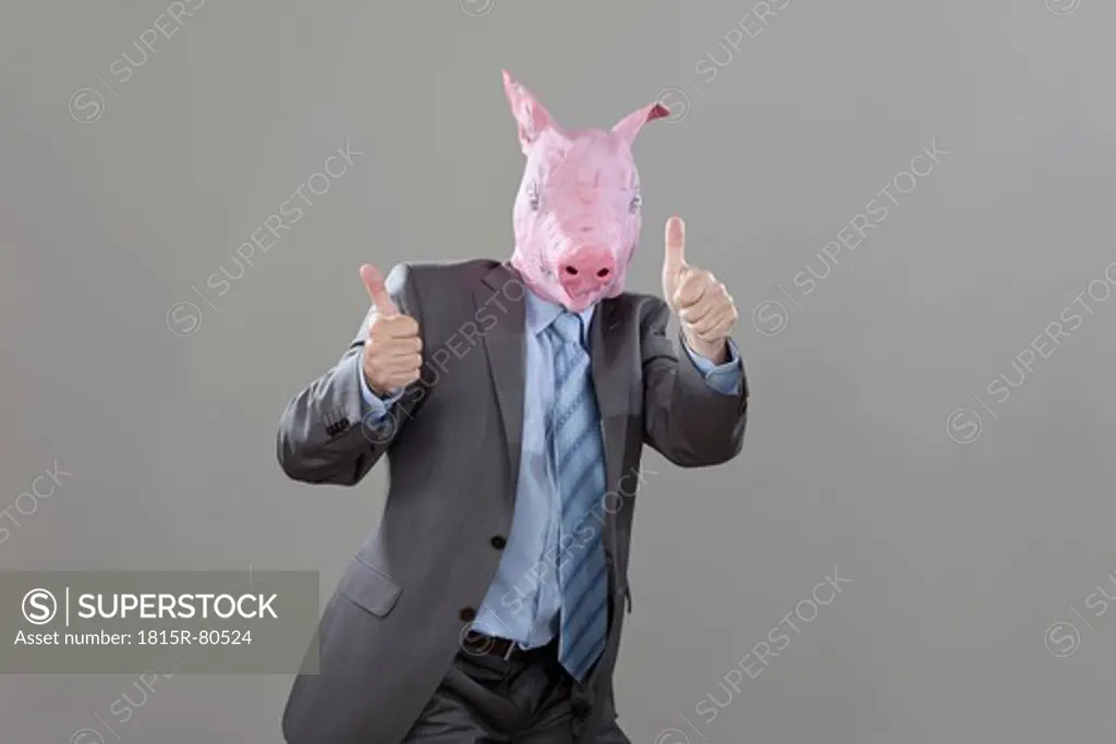 Businessman with pigs head with thumbs up in office against grey background
