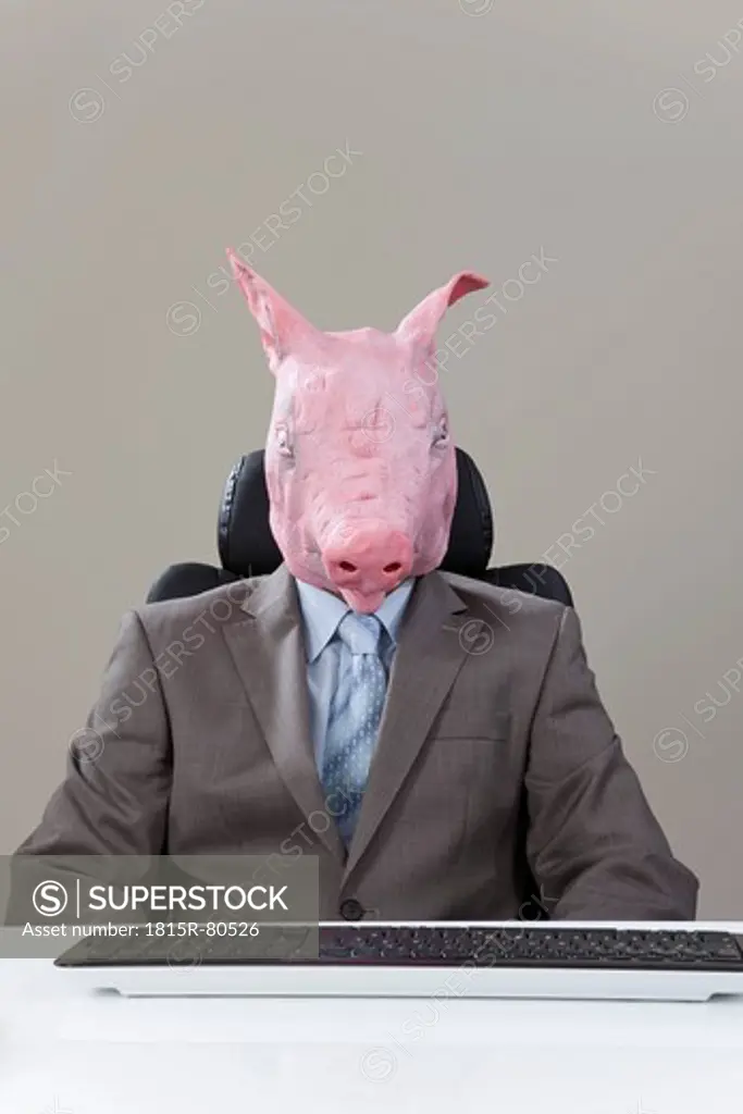 Close up of businessman with pigs head with keyboard in office against grey background