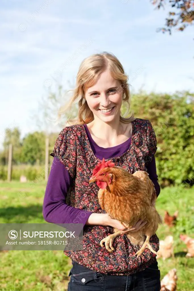 Germany, Saxony, Young woman with hens, portrait, smiling