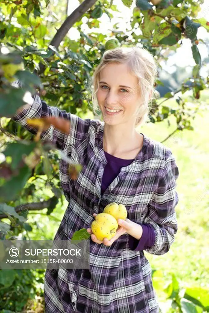 Germany, Saxony, Young woman holding vegetable, smiling, portrait