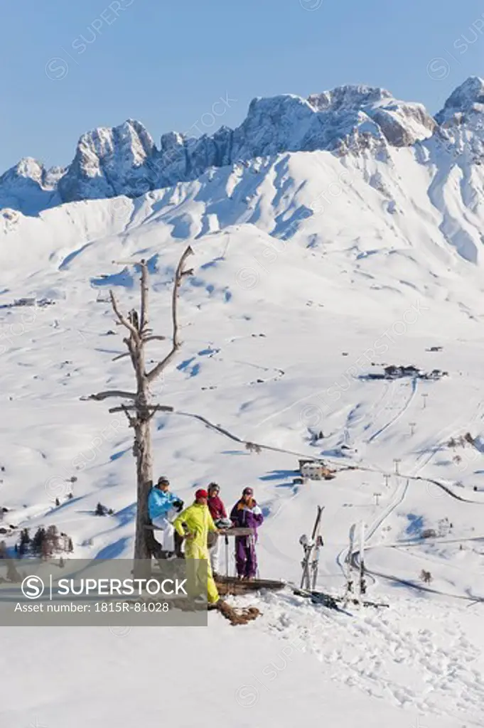 Italy, Trentino_Alto Adige, Alto Adige, Bolzano, Seiser Alm, People resting near bare tree on snowy landscape