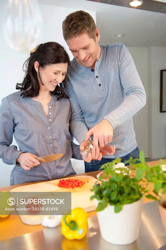 Germany, Munich, Man and woman cooking in kitchen, smiling