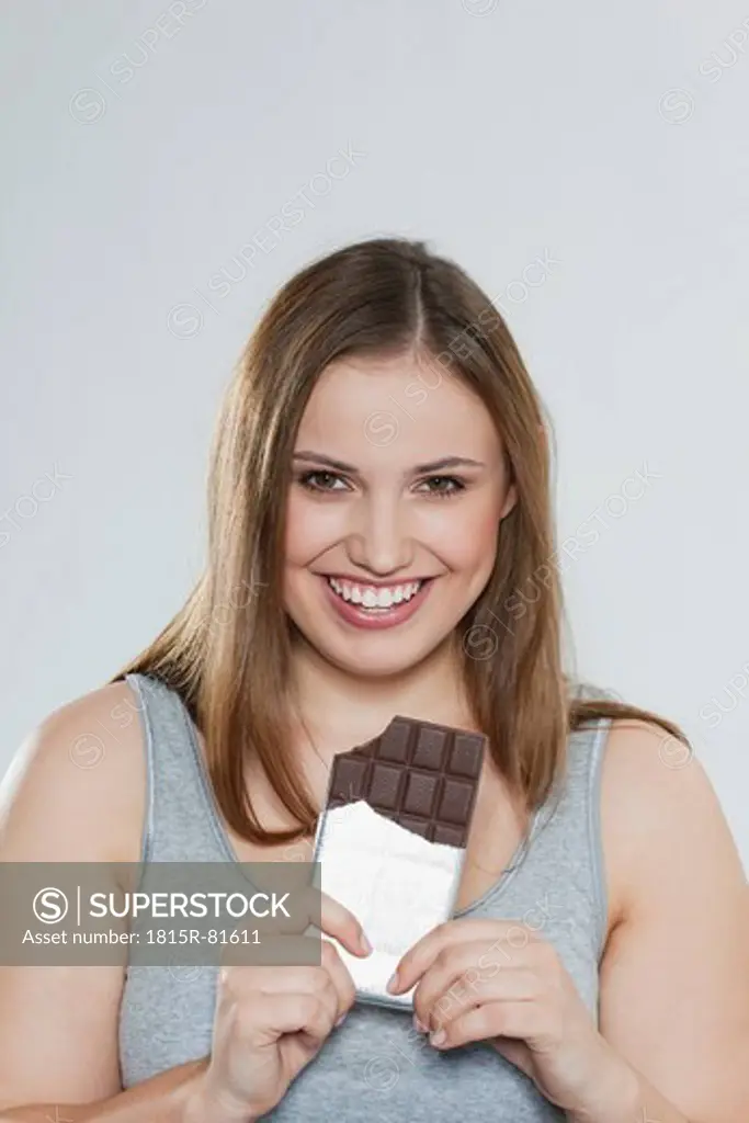 Young chubby woman with chocolate bar, smiling, portrait