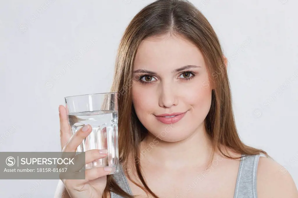 Young woman with glass of water, smiling, portrait