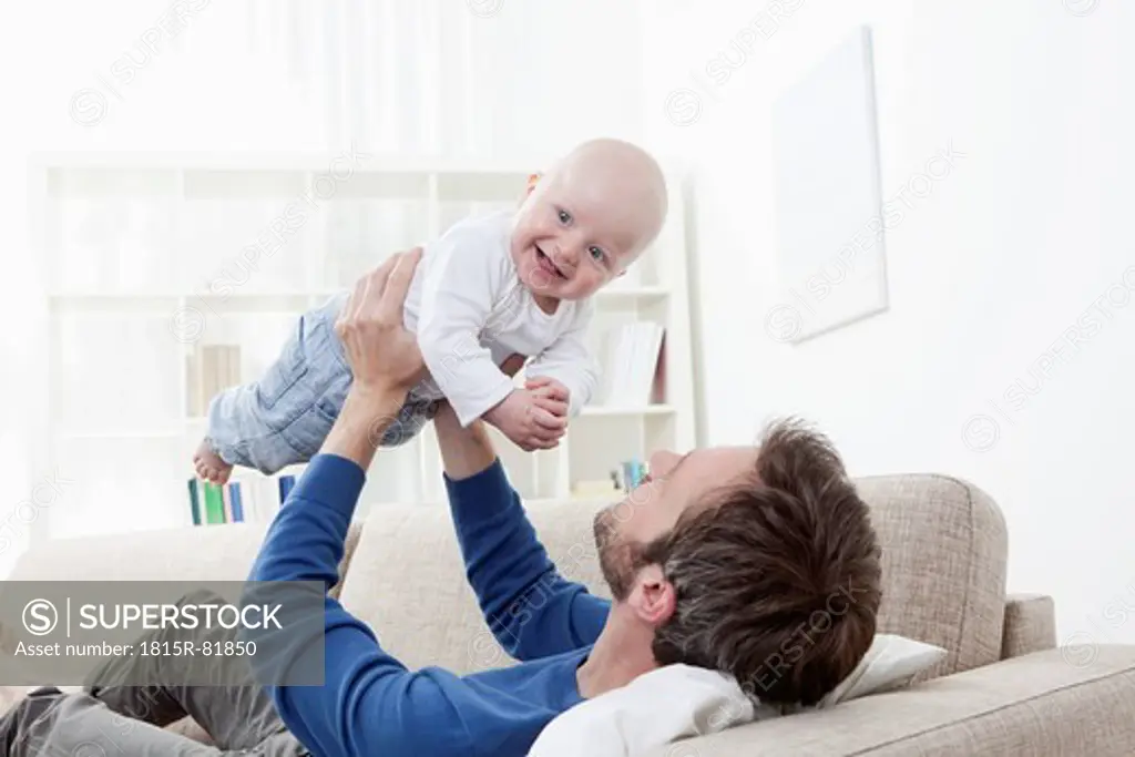 Germany, Bavaria, Munich, Father playing with baby boy 6_11 Months on sofa