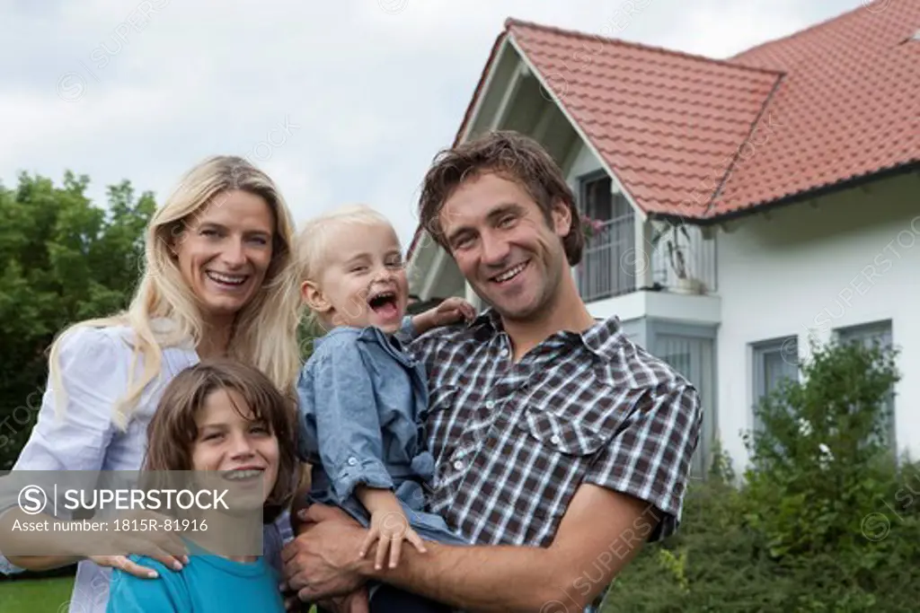 Germany, Munich, Family standing in front of house, smiling, portrait