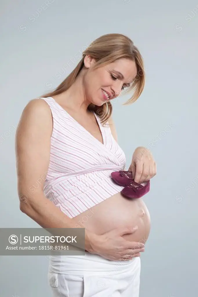 Pregnant mid adult woman with baby shoes