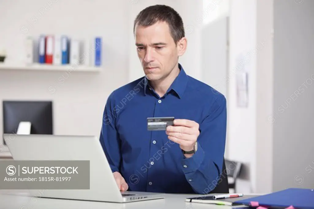Germany, Bavaria, Munich, Businessman in office with credit card