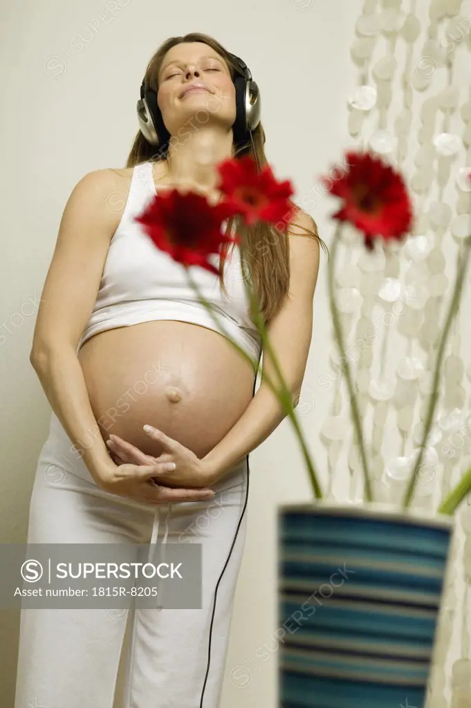 Pregnant woman wearing head phones, smiling