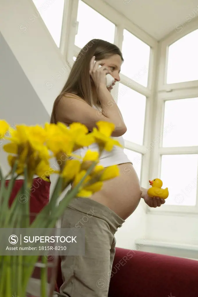 Pregnant woman using telephone, side view