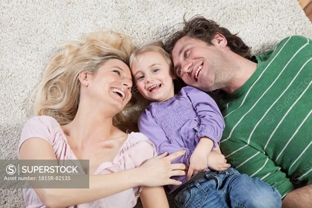 Germany, Bavaria, Munich, Mother tickling daughter with father beside, laughing