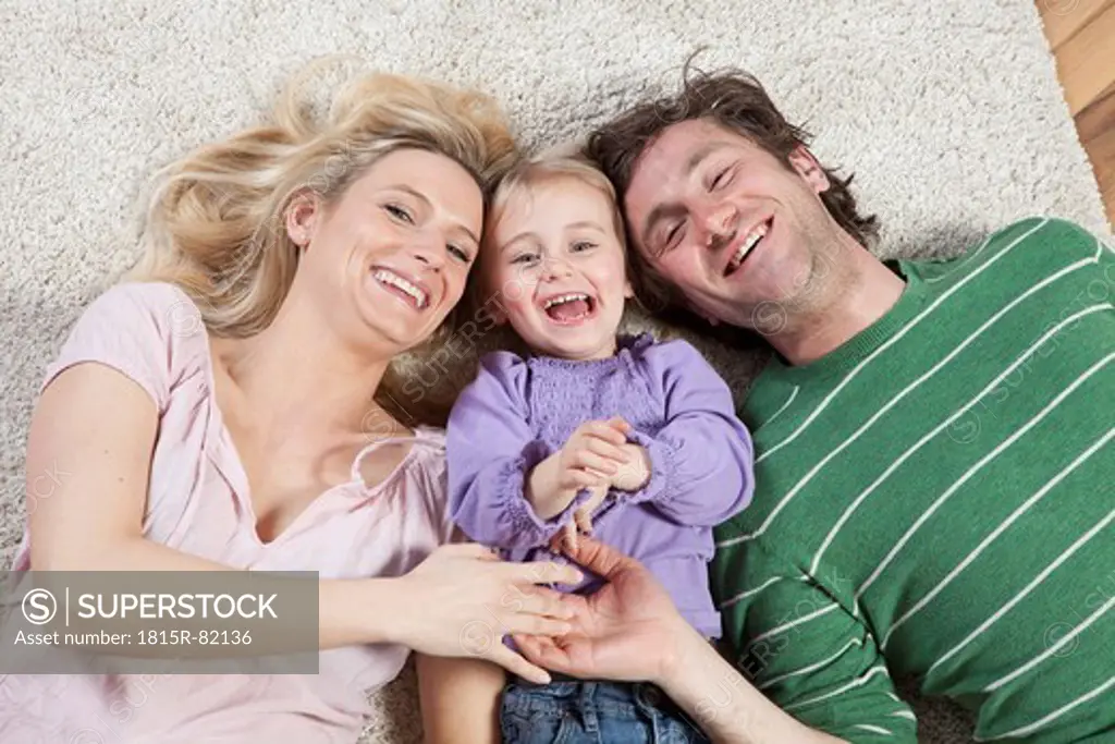 Germany, Bavaria, Munich, Family lying on carpet, smiling, portrait