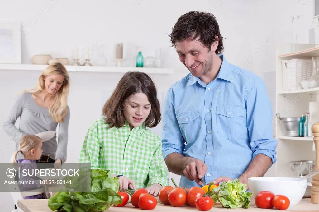 Germany, Bavaria, Munich, Son preparing salad with father, mother and daughter in background