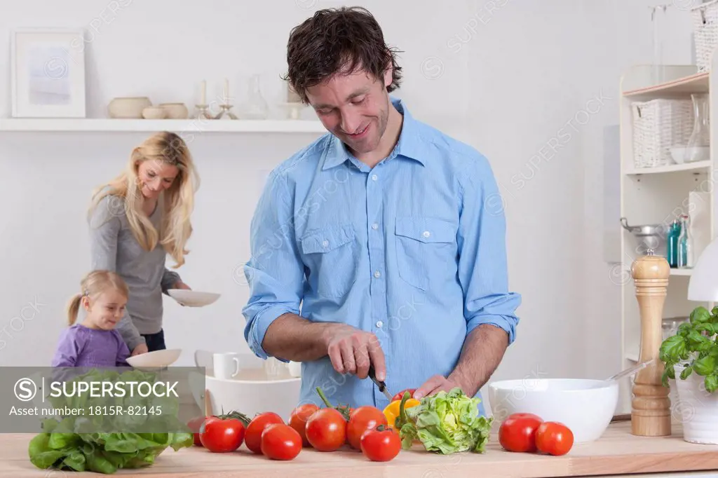 Germany, Bavaria, Munich, Father preparing salad with mother and daughter in background