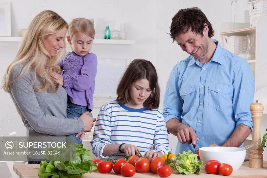 Germany, Bavaria, Munich, Son preparing salad with father, mother and daughter standing besides them