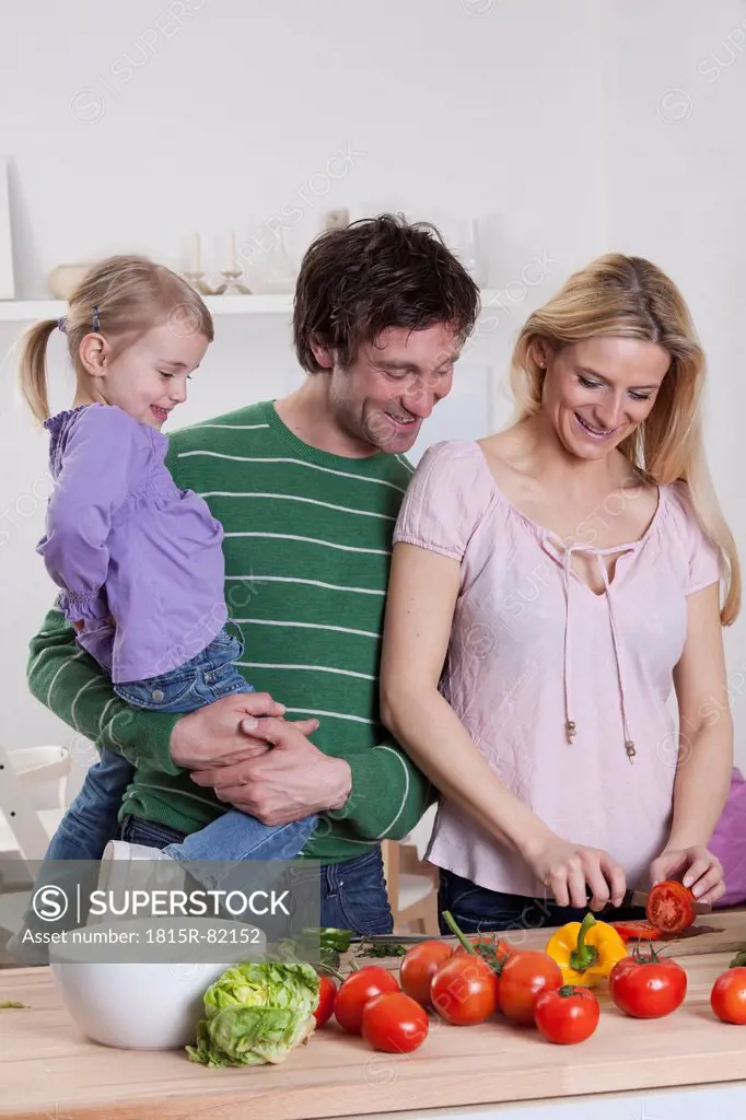 Germany, Bavaria, Munich, Mother preparing salad with father and daughter standing beside her