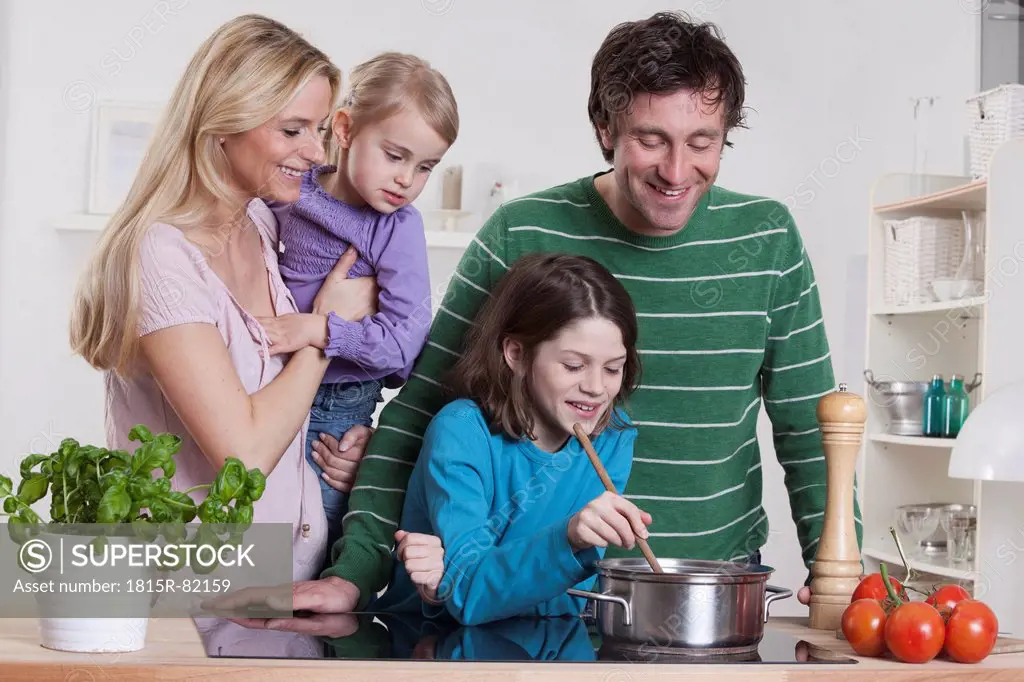 Germany, Bavaria, Munich, Son cooking with father, mother and daughter standing besides them