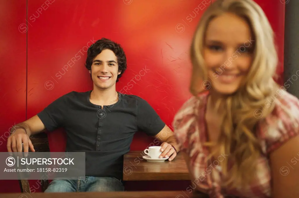 Germany, Munich, Young man smiling with teenage girl in foreground