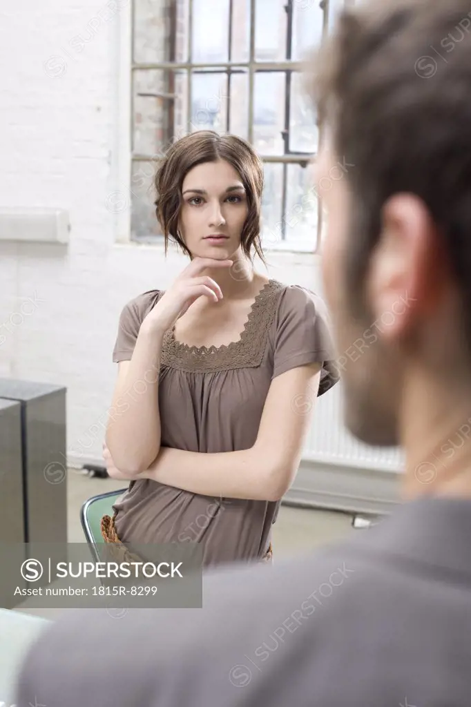 Two business people in office, woman looking sceptical
