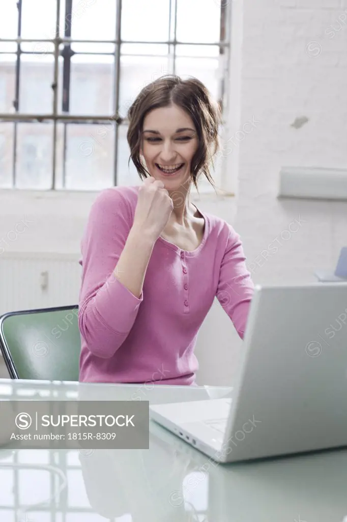Young businesswoman in office, clenching fist