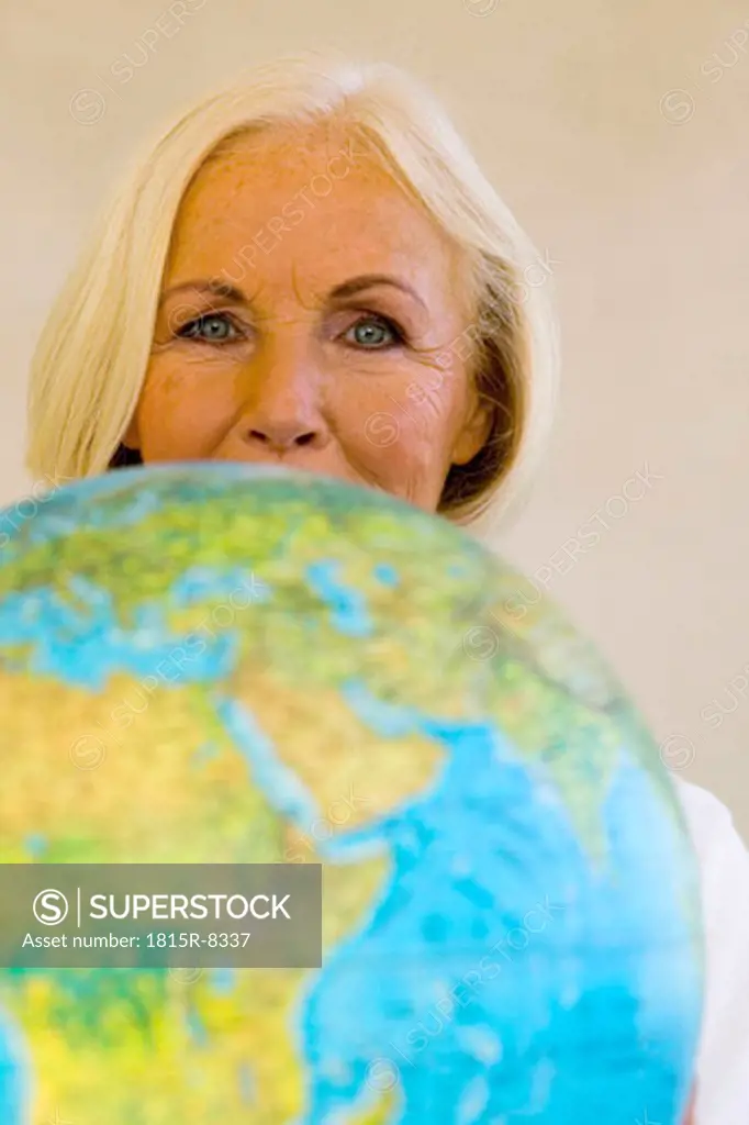 Senior woman holding globe, portrait, close-up