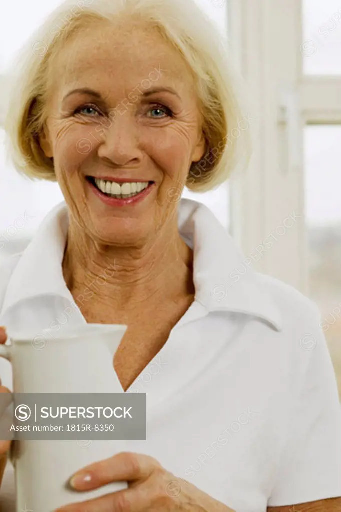 Senior woman holding jug, smiling, close-up, portrait