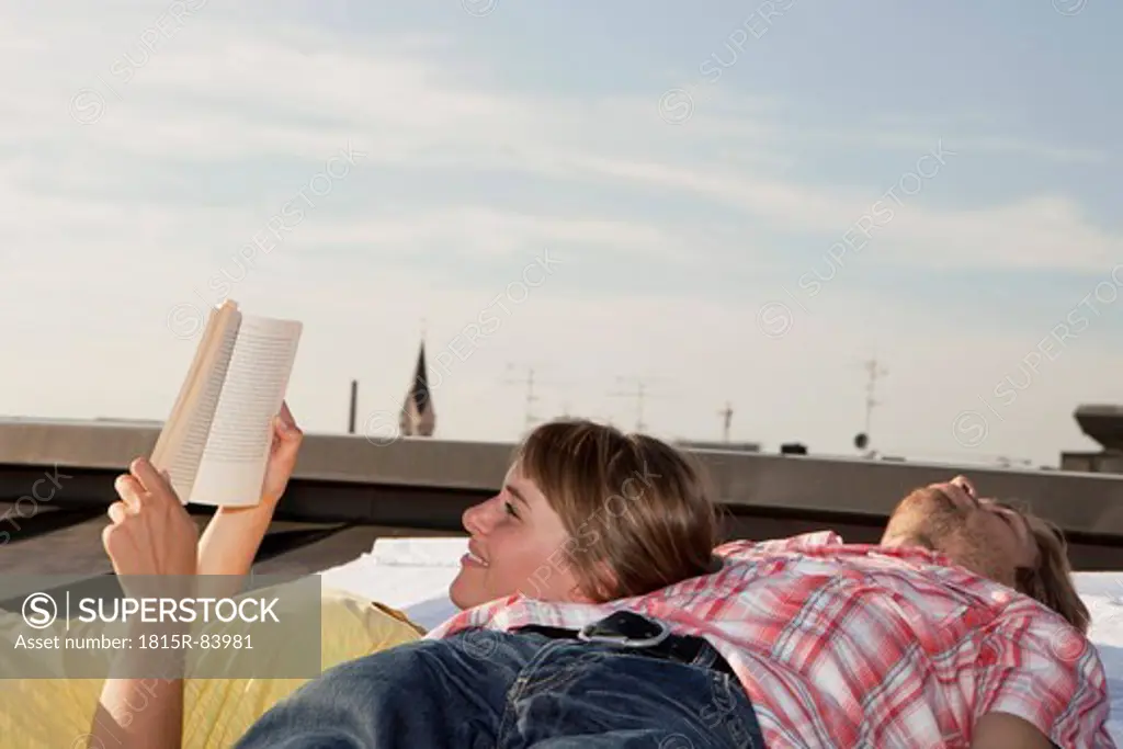 Germany, Bavaria, Munich, Young couple relaxing on rooftop
