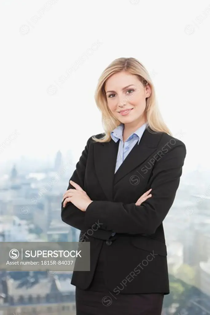 Germany, Frankfurt, Business woman smiling with arms crossed, portrait