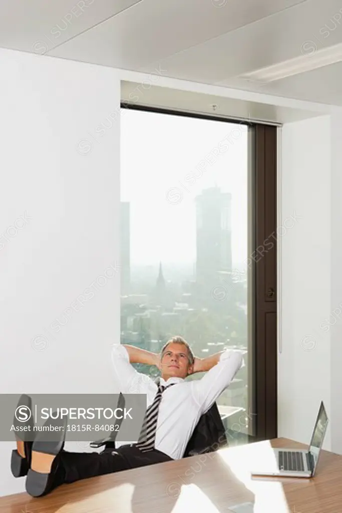 Germany, Frankfurt, Businessman resting in office with laptop on table