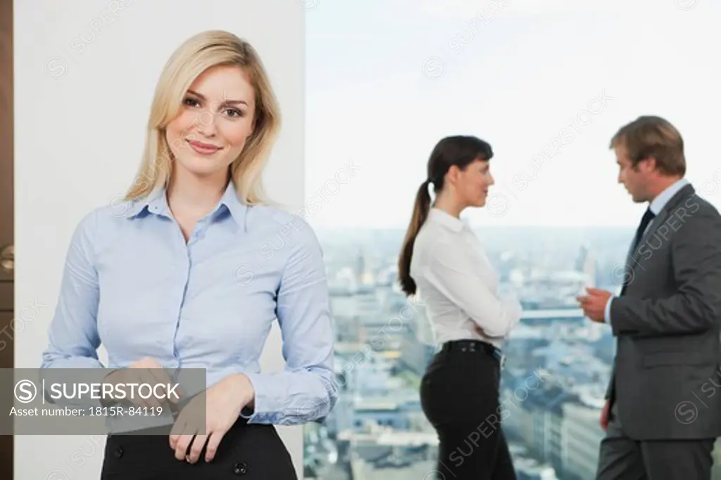 Germany, Frankfurt, Business woman smiling with business people talking in background