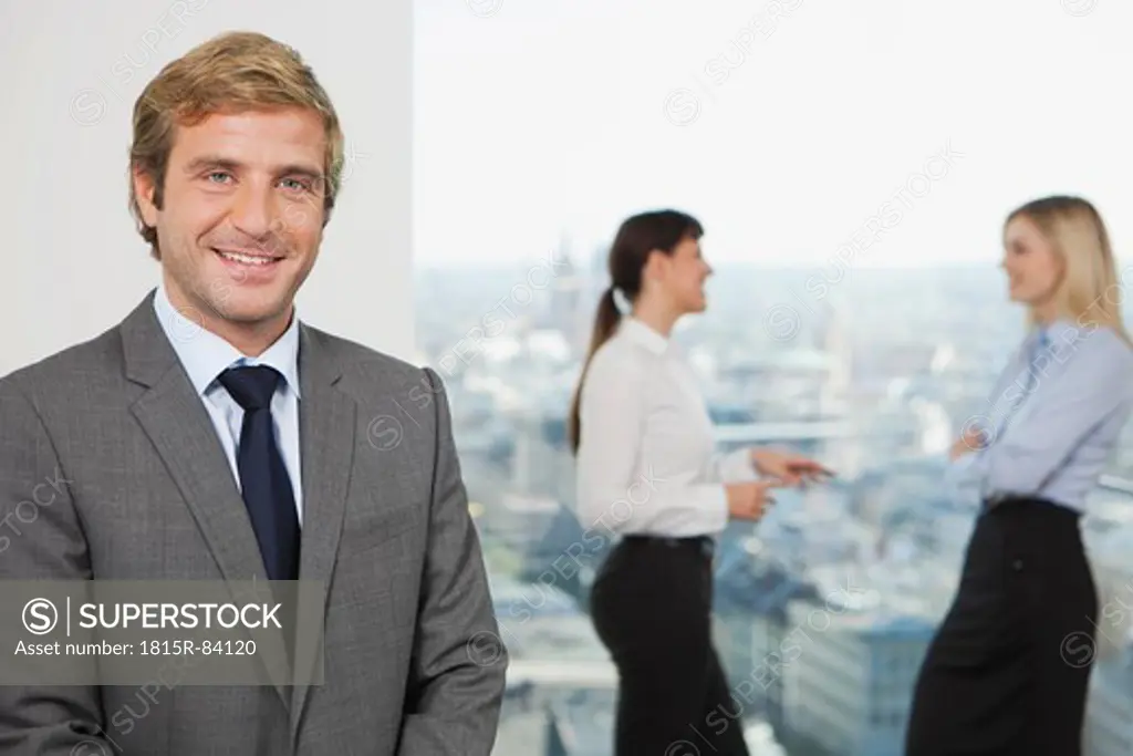 Germany, Frankfurt, Business man smiling with business people talking in background