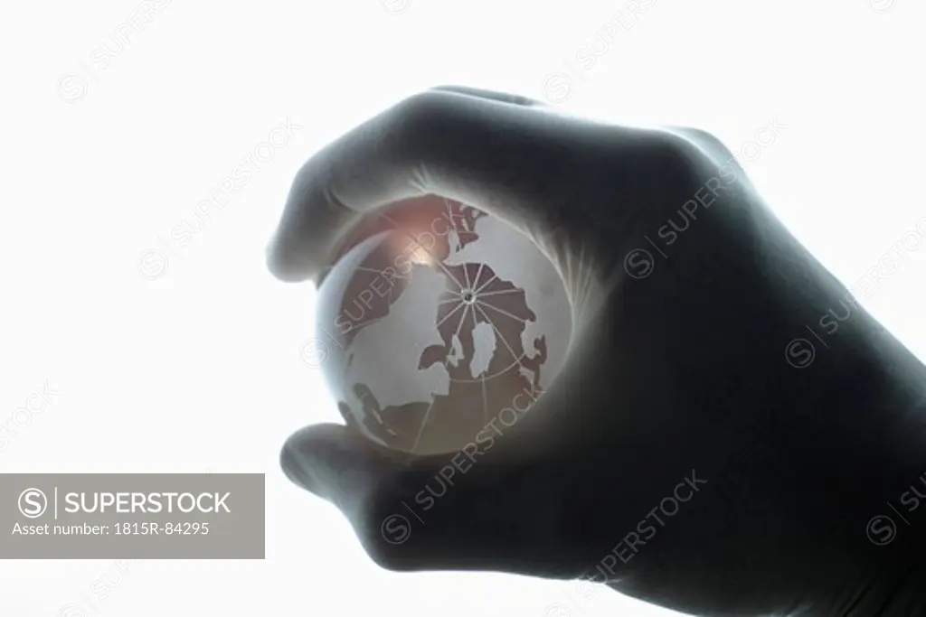 Human hand with medical gloves gripping glass globe against white background, close up