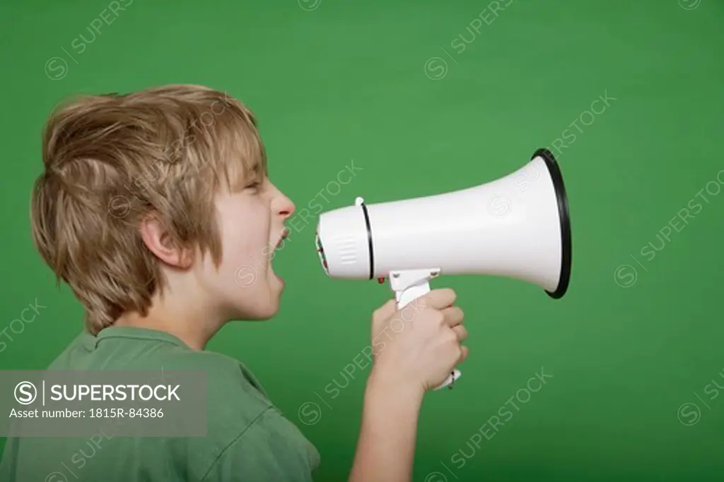 Close up of boy screaming in megaphone against green background