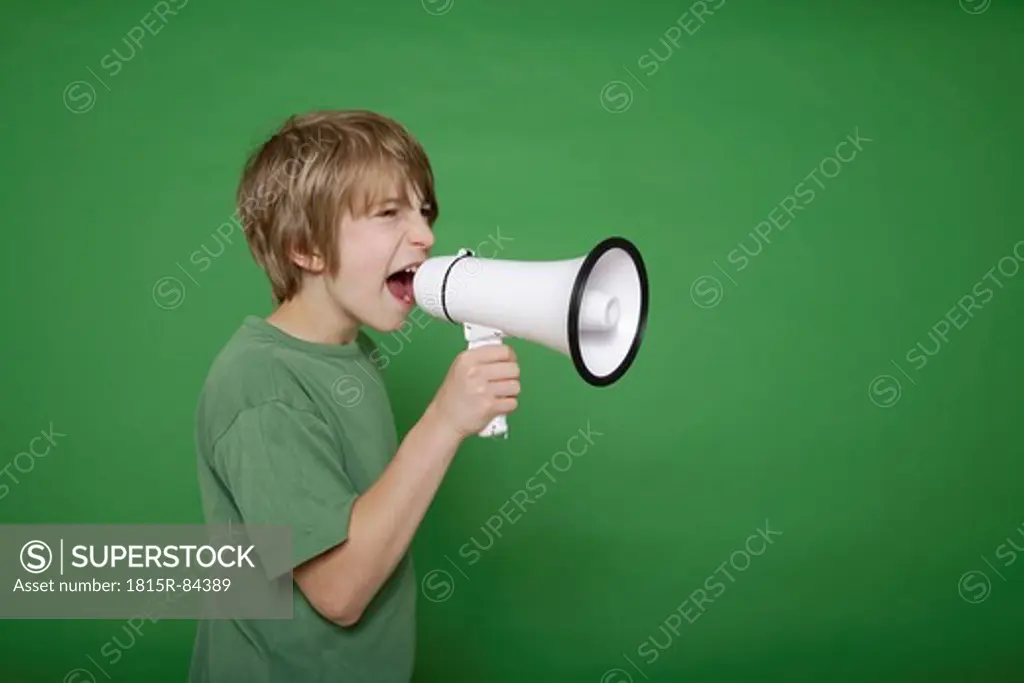 Boy screaming in megaphone against green background