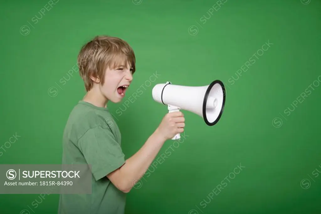 Boy screaming in megaphone against green background
