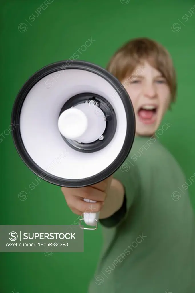 Boy screaming in megaphone against green background