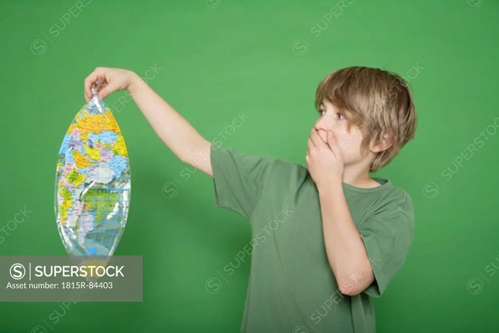 Boy holding deflated air globe against green background